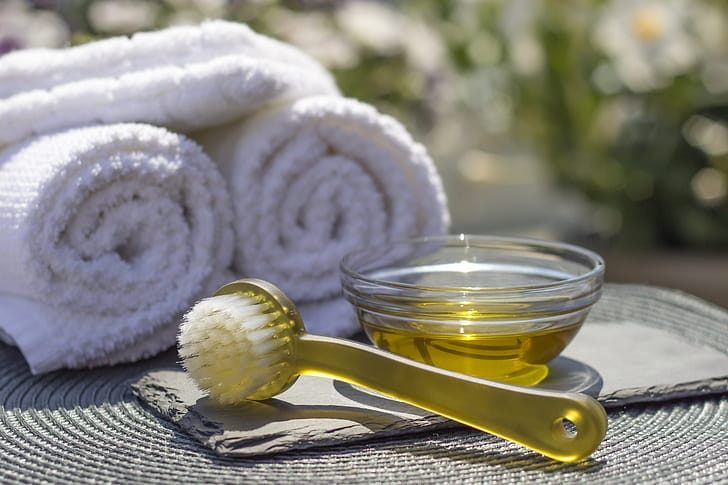 Óleo dourado e toalhas preparados para uma sessão de massagem com mel